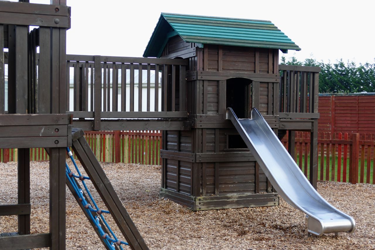 Mastering the First Impression: Your intriguing post title goes here A wooden playground structure with a slide in an outdoor park, ideal for children.